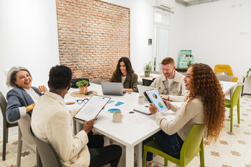 Fototapeta premium Group of happy business professionals brainstorming and analyzing data charts in a modern office workspace