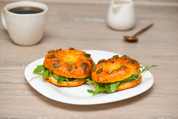 Homemade bagels with cream cheese, fish and arugula in a plate with cup of coffee. Fresh breakfast.
