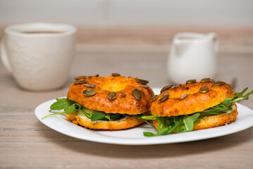 Bagels with cream cheese, fish and arugula in a plate with cup of coffee. Fresh breakfast.