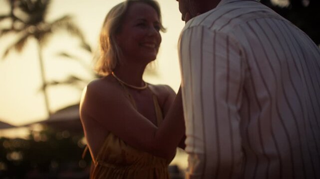 Happy couple dancing and enjoying cocktails at sunset during a romantic tropical vacation