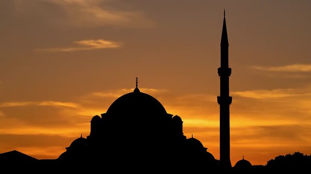 Silhouette of a mosque with a dome and minaret at sunset.