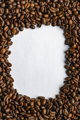 Coffee beans in the shape of a frame on white paper.