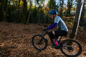 Fototapeta premium Mountain Bike Rider Through Autumn Forest Trail Among Fall Leaves — Outdoor Adventure and Fitness