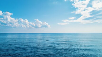 Obraz premium A serene ocean landscape with calm waters under a blue sky with fluffy white clouds