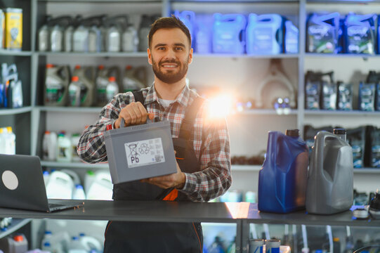 Mechanic holding car battery in auto parts store