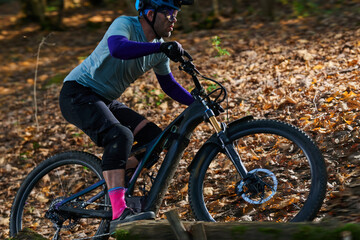 Fototapeta premium Mountain Biker Navigating Forest Trail On Offroad Terrain During Autumn Leaves And Gear