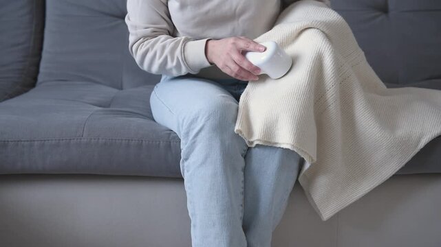 Woman using electric fabric shaver removing pills from sweater