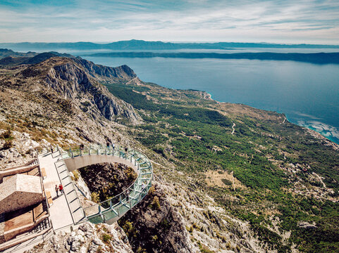 Aerial view of the glass walkway stretching out over the rugged cliffs, meeting the azure sea under a clear sky, Biokovo, Splitsko-dalmatinska &Aring;&frac34;upanija, Croatia.