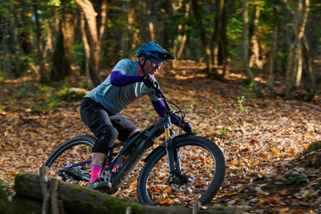 Fototapeta premium Intense Mountain Biker Navigates Leafy Forest Trail With Focus, Gear, and Adrenaline