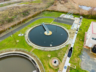 Water treatment facility in an industrial area near a wetland with multiple tanks and green surroundings during daylight