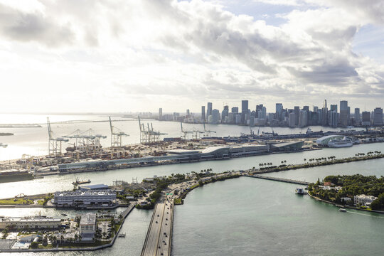 Aerial view of a bustling port with towering cranes meeting the distant skyline, a vibrant mix of industry and nature, South Beach, Miami Beach, Florida, United States.