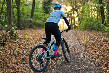 Fototapeta premium Autumn Forest Mountain Biking: Rider on Trail With Helmet, Gear, And Colorful Socks