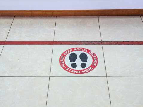 Social Distancing Floor Decal with Footprint Icons and Safety Warning Message on Tiled Surface for Health Protection