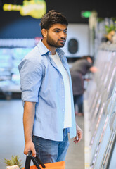 Customer choosing frozen food in supermarket refrigerator section