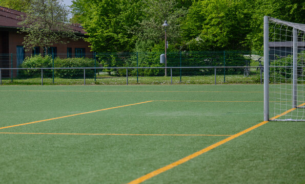 Nahaufnahme eines Fu&szlig;ballfeldes mit Kunstrasen und orangefarbenen Streifen