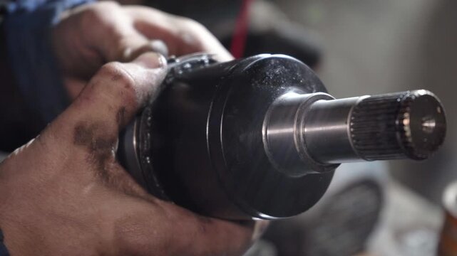 A service station worker installs a new SHRKSh on the drive shaft, Mechanic changes grenade internal SHRKSh, Car repair: replacement of internal SHRKSh