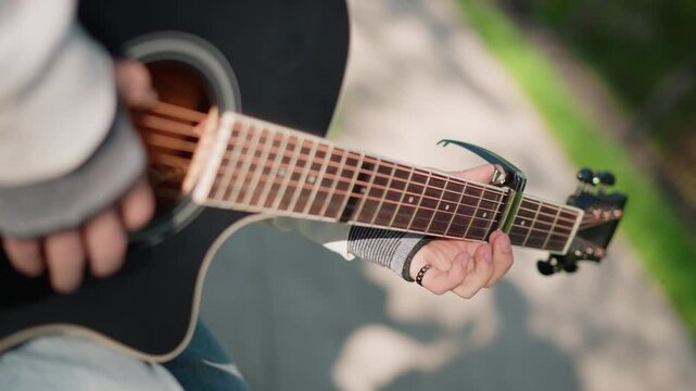 park black guitarist strumming acoustic guitar, dynamic sidewalk busker performance with visible soundhole, fingerless glove and denim, warm sunlight and bokeh, upbeat rhythm and lively melody, street