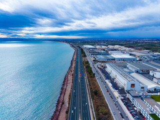 Large road runs along the waterfront with buildings and factories nearby in an industrial area