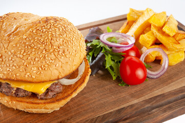 Hamburger with potatoes and vegetables on a wooden board