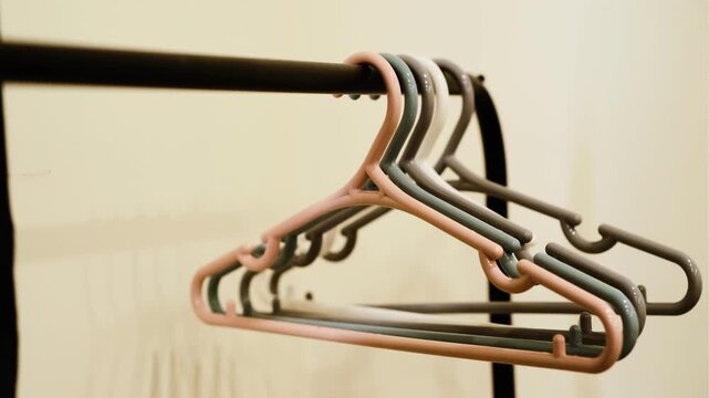 A close-up shot of a row of colorful plastic coat hangers hanging on a black metal rack. Clean, minimalist background, perfect for lifestyle or retail imagery.