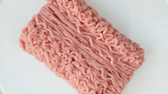 Fresh minced poultry meat rotating on white background.