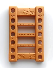 A tan-colored plastic object with holes and indented lines on a white background