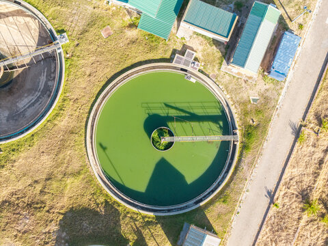 Aerial view of the circular treatment pools shimmering with green hues contrasting against the arid landscape, Kraaifontein, Western Province, South Africa.