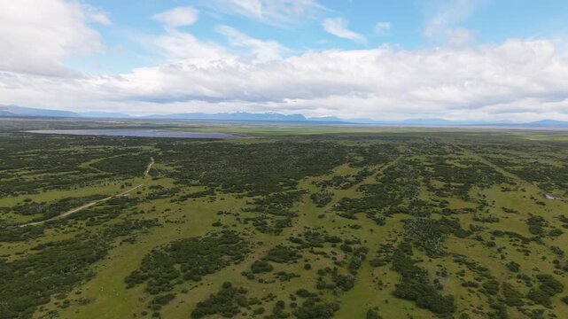 Wide aerial view of Chilean Patagonia near &Uacute;ltima Esperanza, Magallanes&mdash;open steppe and lagoons with distant Andes under dramatic clouds.