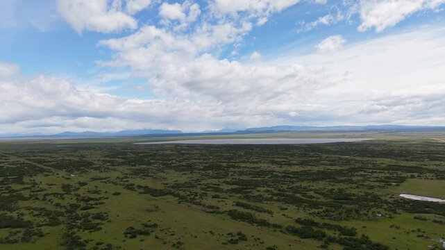 Wide aerial view of Chilean Patagonia near &Uacute;ltima Esperanza, Magallanes&mdash;open steppe and lagoons with distant Andes under dramatic clouds.