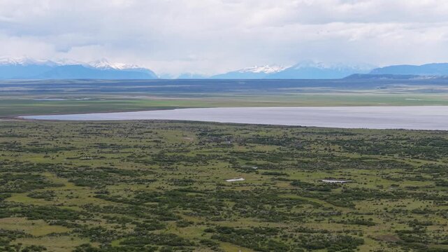 Aerial view of Patagonian steppe and grazing farmland near &Uacute;ltima Esperanza, Magallanes, Chile&mdash;green scrub plains and distant Andes under a cloudy sky.
