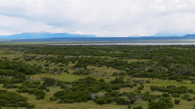 Aerial view of Patagonian steppe and grazing farmland near &Uacute;ltima Esperanza, Magallanes, Chile&mdash;green scrub plains and distant Andes under a cloudy sky.