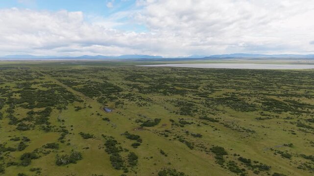 Wide aerial view of Chilean Patagonia near &Uacute;ltima Esperanza, Magallanes&mdash;open steppe and lagoons with distant Andes under dramatic clouds.