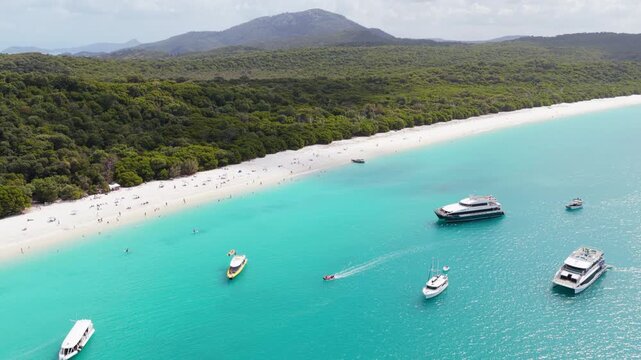 Wide aerial of boats, tourists and snorkelers at Whitehaven beach in the Whitsunday Islands, Australia, a pristine landscape famous for its pure silica sand and crystal-clear turquoise waters.
