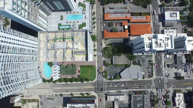 Drone top-down view of Miami city blocks with rooftops, pools and moving traffic.