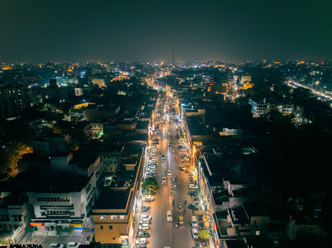Aerial view of the illuminated city at night with a long road with vehicles and buildings on both sides, Jaipur, Rajasthan, India.