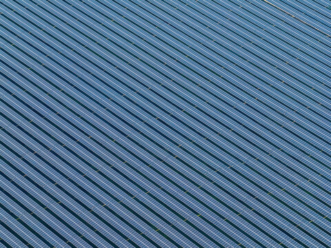Aerial view of rhythmic blue solar panels stretch across the landscape, creating a mesmerizing pattern of light and shadow, Wittelsheim, Grand Est, France.
