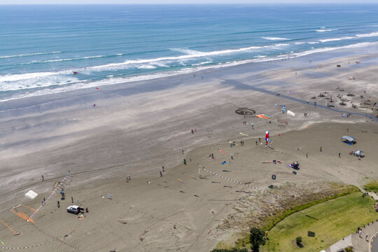 Aerial view of the shoreline contrasts with the deep blue of the ocean, while people enjoy the beach activities on the sandy expanse, Whakatane, Bay of Plenty Region, New Zealand.