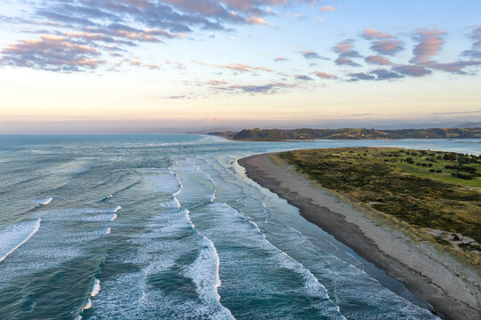 Aerial view of a tranquil coastline where the river meets the sea under a soft, pastel sky, Whakatane, Bay of Plenty Region, New Zealand.