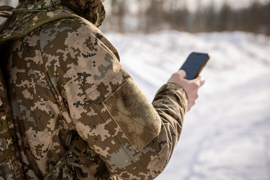 Military Soldier Using Phone for Comunication and Navigation in Winter Snow. 5G for Military Communications. 