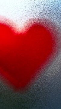 Vertical video: Moving camera showing red heart decal changing focus on pebbled frosted panel, halo
