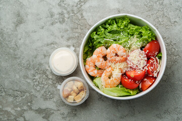 Fresh shrimp salad with lettuce and tomatoes served in a bowl with dressing and croutons