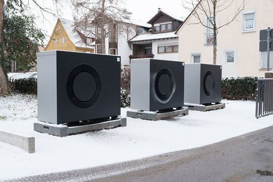 Row of modern heat pumps outside residential buildings in winter