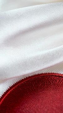 Vertical video: Camera shifting white satin showing red stitched patch on table indoors for detail