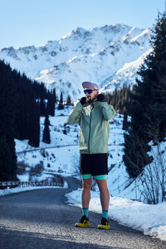 Man running on the road in the winter mountains