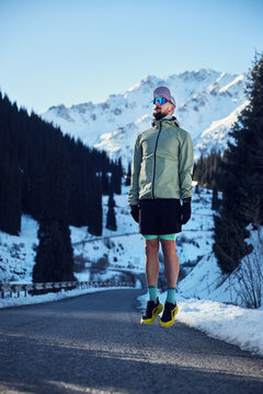 Man running on the road in the winter mountains
