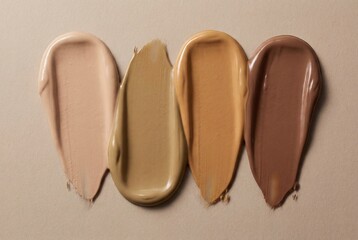 Fototapeta premium Four creamy makeup foundation swatches showing diverse skin tones on beige paper