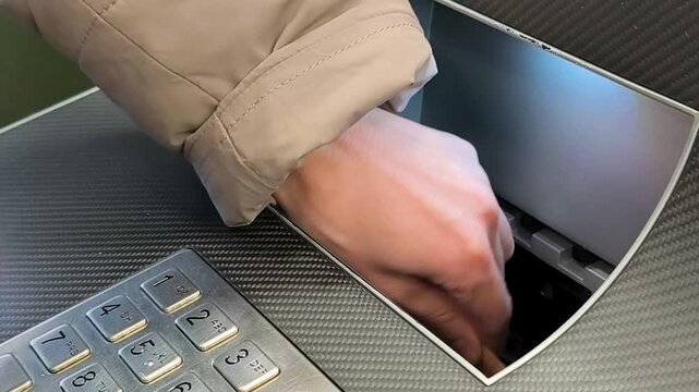 Woman Depositing Russian Ruble Banknotes into ATM. Close-up of a hand inserting 5000 Russian ruble banknotes into the cash deposit slot of an ATM machine. Financial and banking service concept