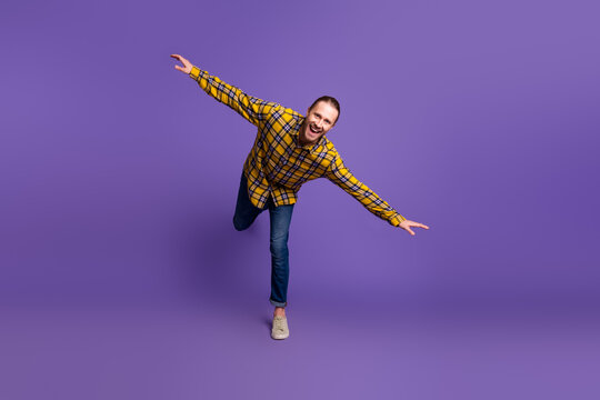 Young handsome guy in plaid shirt jumps with joy against purple background suitable for lifestyle advertising