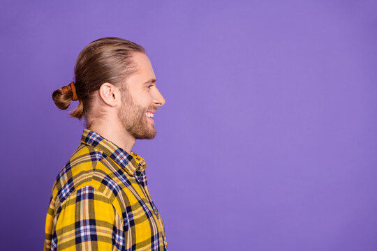 Young handsome guy in yellow plaid shirt smiles in profile against purple background for lifestyle fashion and advertising