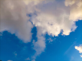 Bright blue sky background with fluffy white and grey cumulus clouds. Perfect for weather, nature, or background use.